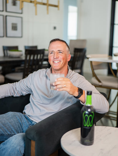 A high-quality photo of MonaVie Active being enjoyed in a bright, modern setting, representing real customer wellness experiences and a premium botanical lifestyle