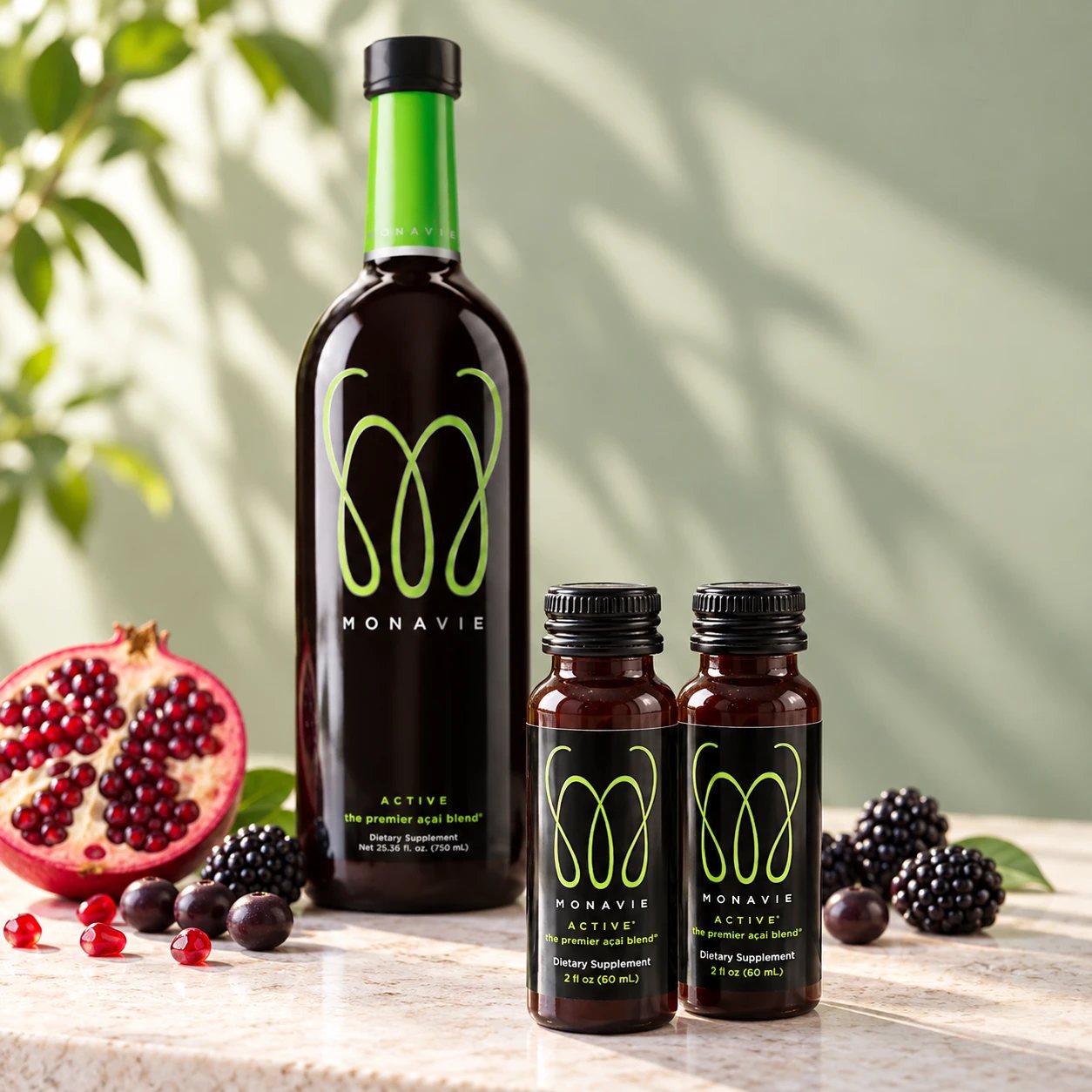 Two new MonaVie Active 2 oz shots in front of the original 25 oz bottle with pomegranate, açaí berries and blackberries