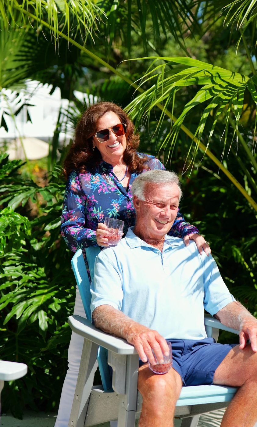 Smiling couple relaxing in a sunny garden with glasses of MonaVie